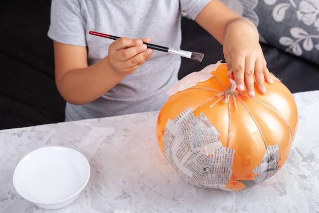 子供は風船に接着剤を塗って紙片を貼り付け 張り子からカボチャを作ります プレミアム写真