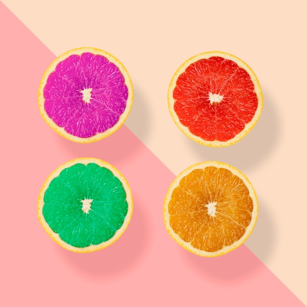 パステルカラーの背景に創造的な幻想的な4つのオレンジ色の果物 紫赤緑とオレンジ色の果物 プレミアム写真