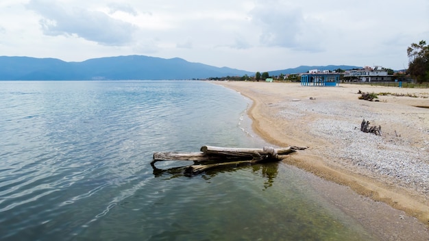 ビーチ エーゲ海の海岸 建物や丘 アスプロバルタ ギリシャの枯れ木の幹 無料の写真