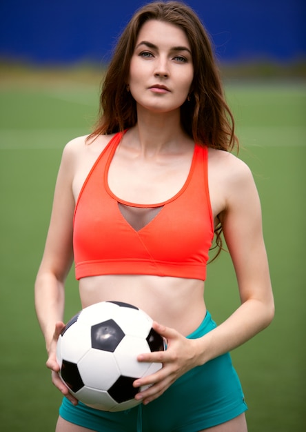 トップとショートパンツの女子サッカー選手が手にボールを保持 プレミアム写真