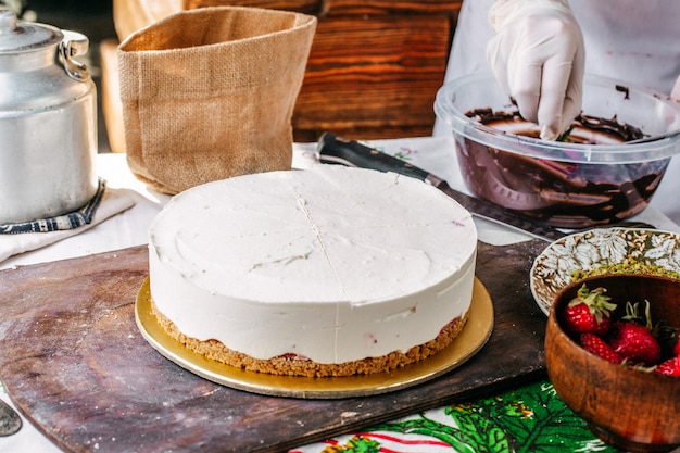 クリームの丸いケーキを美味しい誕生日のお祝いに甘いものにする過程でケーキチョコとイチゴのケーキを作る正面図クック 無料の写真