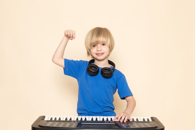 無料の写真 小さなかわいいピアノを弾く黒いヘッドフォンで青いtシャツに笑みを浮かべて正面かわいい男の子