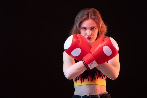 赤いボクシンググローブの正面若い魅力的な女性は黒の背景のスポーツボクシングトレーニングにシャツを火します 無料の写真