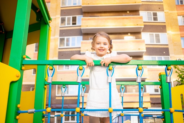 幸せな子供の女の子は庭で夏に家の近くの子供の複雑な遊び場で遊んで 笑顔 プレミアム写真