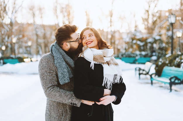 冬に公園で女性が男に頬にキスをする幸せな抱き合うカップル プレミアム写真