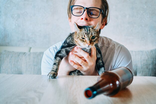 酔っ払った男が猫を抱っこしている プレミアム写真