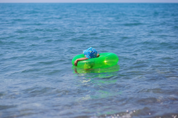 小さな子供が一人で海の真ん中にあるゴムの輪に浮かぶ プレミアム写真