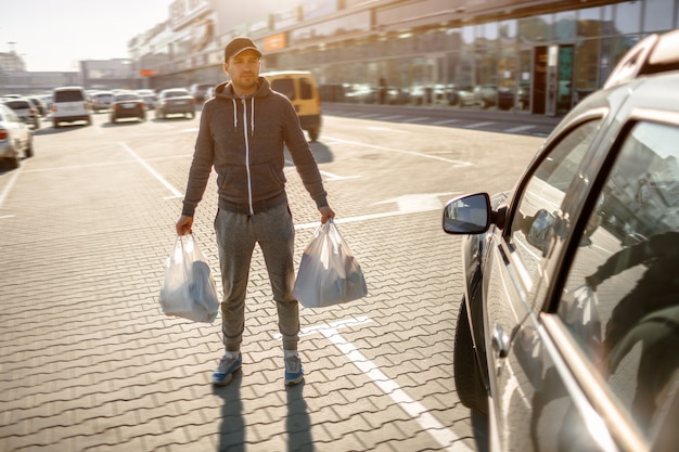 ショッピングセンターやショッピングモールの近くの駐車場に男が立っている プレミアム写真