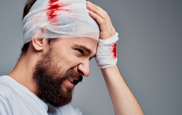 腕に包帯を巻いた頭の血液蘇生手術モデルのガーゼを持った男性 プレミアム写真