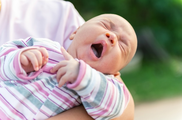 母親の腕の中であくびをしている生まれたばかりの赤ちゃん プレミアム写真