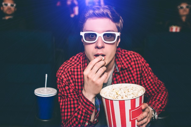 映画館の椅子に座っているとポップコーンを食べている男の肖像 プレミアム写真