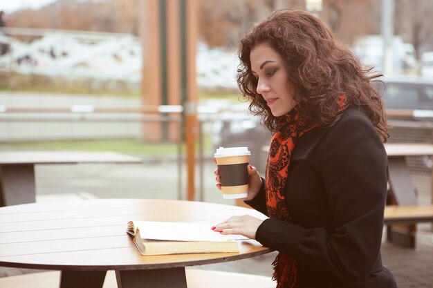 きれいな女性がカフェショップのテラスで本を読む プレミアム写真