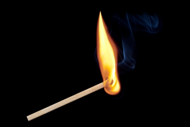 黒の背景に孤立して立ち上がる炎と煙との単一の燃えるマッチ プレミアム写真