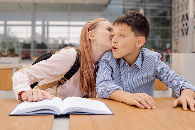 10代の女子高生が男の子の耳に何かをささやいたり キスしたりしています プレミアム写真