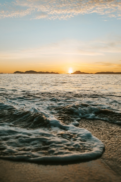 カラフルな夕日の間に砂の上のビーチの潮の垂直方向の画像 プレミアム写真