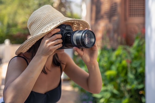 帽子をかぶった若い女性が暑い夏の日にプロの一眼レフカメラで写真を撮る 無料の写真