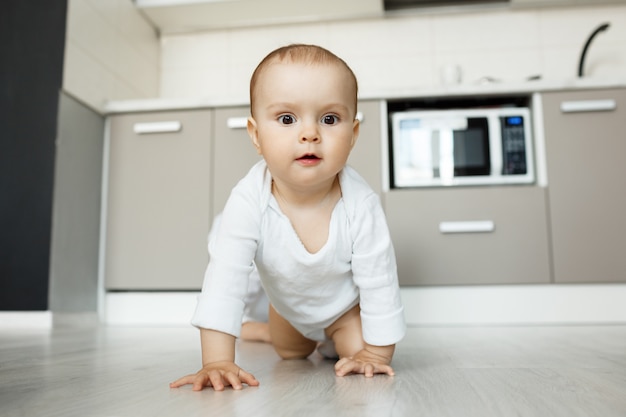 面白がって顔をキッチンの床の上でクロールかわいい赤ちゃん 無料の写真