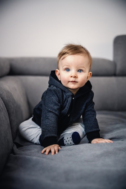 Premium Photo Adorable Blond Little Boy With Beautiful Blue Eyes Sitting On Sofa