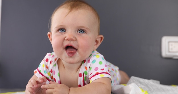 Adorable grimacing funny baby in rompers showing tongue ...