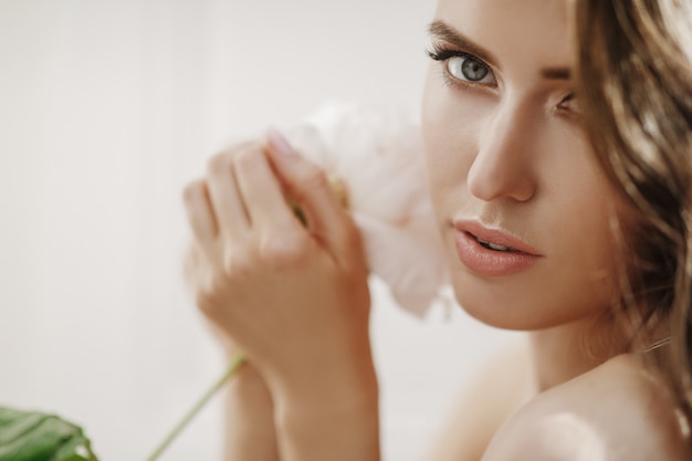 Adorable young woman holds white flower before her face Free Photo
