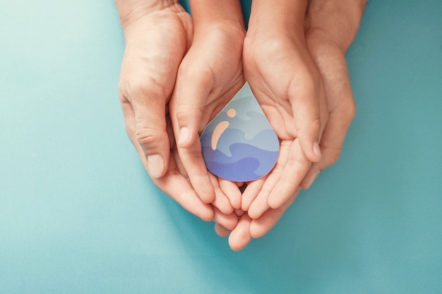 Adult and child hands holding paper cut water drop. world water day. clean water and sanitation, csr, save water. Premium Photo