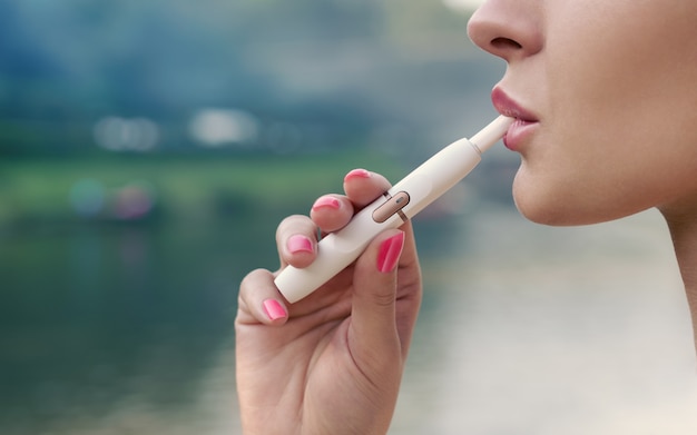 大人の女性の顔の横顔ビュー電子タバコを屋外で喫煙 プレミアム写真