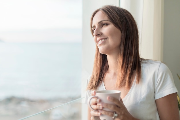 Premium Photo | Adult woman standing while looking through window ...