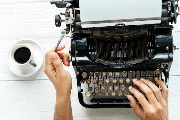 Aerial view of a man typing on a retro typewriter blank paper Free Photo