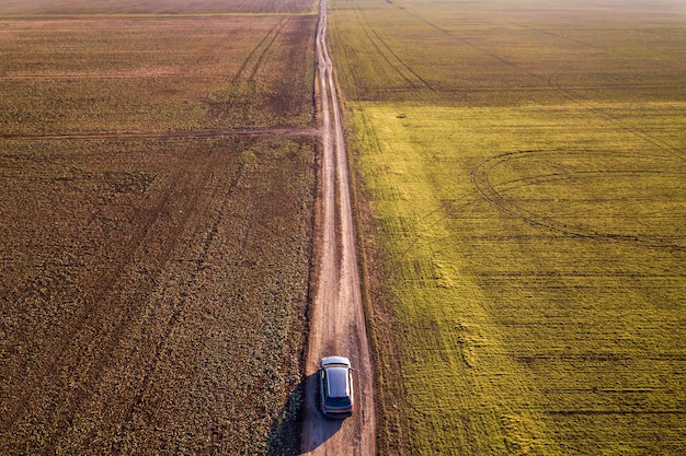 Vid S Vozduha Vozhdeniya Avtomobilya Po Pryamoj Zemnoj Doroge Cherez Zelenye Polya Na Solnechnom Fone Neba Kopii Golubogo Neba Bespilotnaya Fotografiya Premium Foto