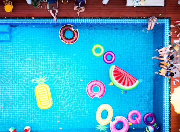 Aerial view of people enjoying the pool with colorful inflatable floats Free Photo