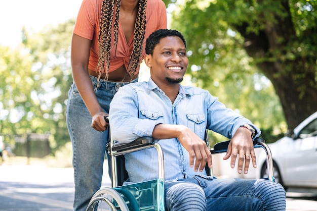 An african american man in a wheelchair enjoying a walk outdoors with his girlfriend Free Photo