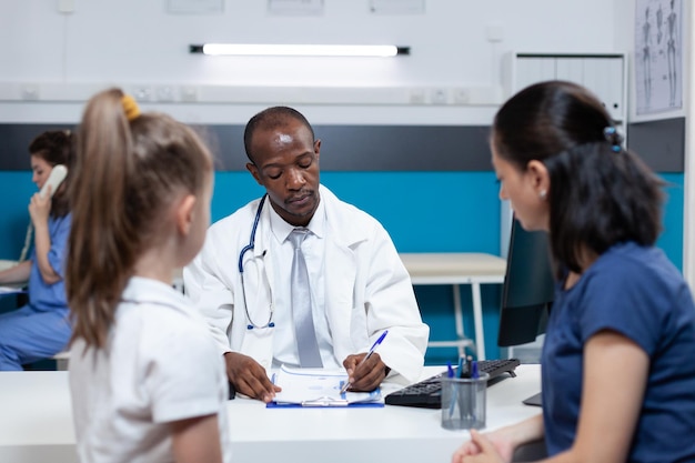 Premium Photo | African american pediatrician doctor writing sickness ...