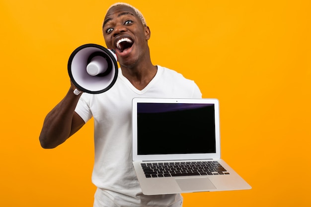 Download African black man with white hair with a megaphone and laptop with a mockup on a yellow studio ...