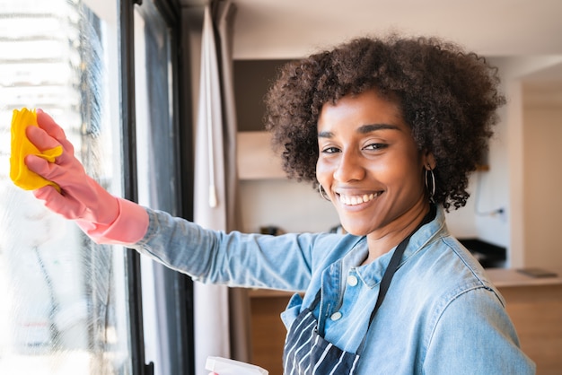 自宅でぼろきれで窓拭きアフロ女性 プレミアム写真
