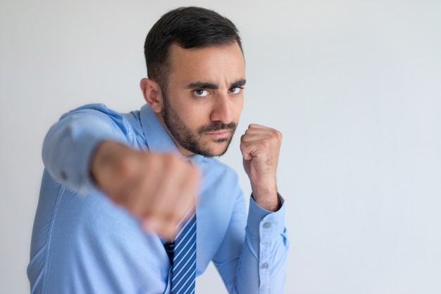 Aggressive young bearded businessman punching camera Free Photo