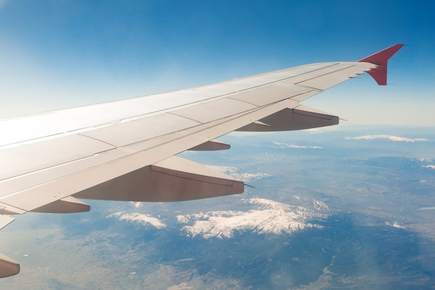 Premium Photo | Aircraft wing on the clouds, flies on the mountains