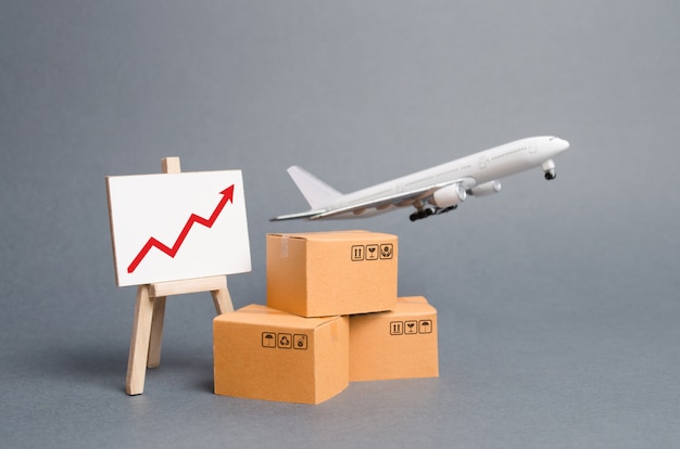 Airplane plane takes off behind stack of cardboard boxes and stand with red up arrow Premium Photo
