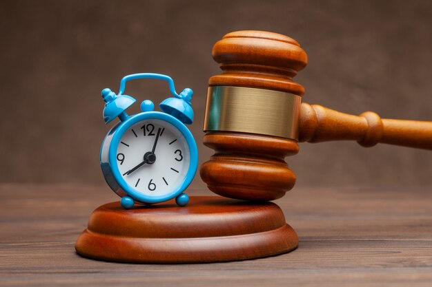 Premium Photo | Alarm clock and hammer judge gavel on brown background