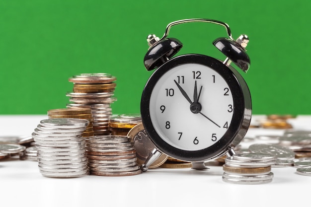 Alarm clock and money coins on the table. | Premium Photo