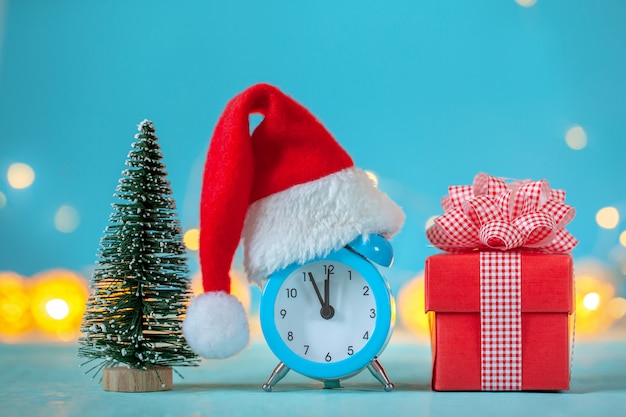 Alarm clock with christmas santa hat and christmas tree and present box. time for christmas. card wi
