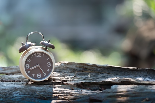 Premium Photo | Alarm clock on wooden table with green nature bokeh ...