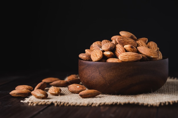 Almonds in a wooden bowl on dark wooden table | Premium Photo