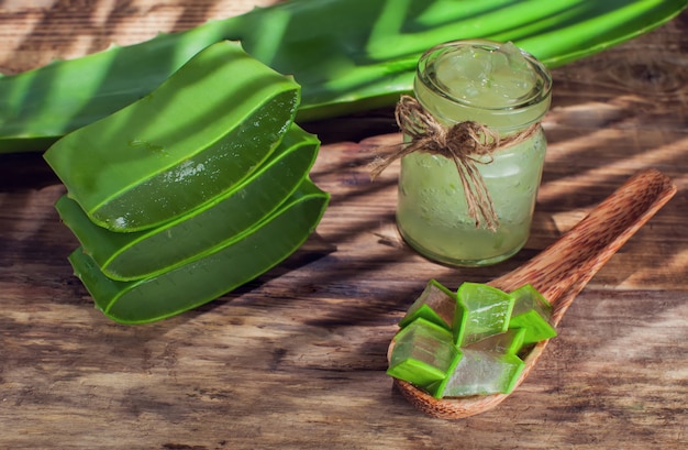 Aloe vera gel and aloe cut pieces on a wooden surface Premium Photo
