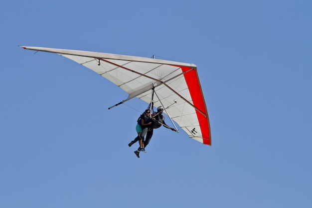 青い空の背景に分離されたハンググライダーで飛んでいる人間の素晴らしい景色 無料の写真