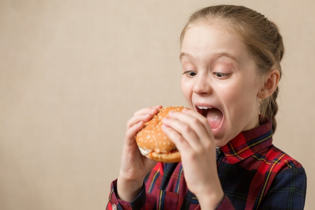 アメリカのカロリー脂肪食事ジャンクフード 小さな女の子ハンバーガーファーストフードハンバーガー不健康な食事を楽しむ プレミアム写真