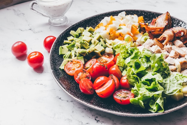 Premium Photo American Traditional Cobb Salad With Chicken Avocado Tomatoes Eggs Bacon And Cheese On A Marble Table Top View