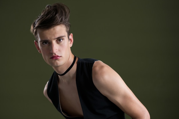 Premium Photo | Androgynous man in waistcoat posing against green wall