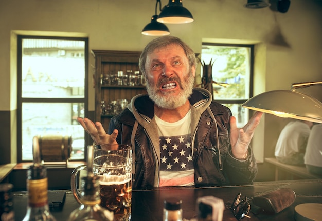 Free Photo | Angry bearded man drinking alcohol in pub and watching a ...