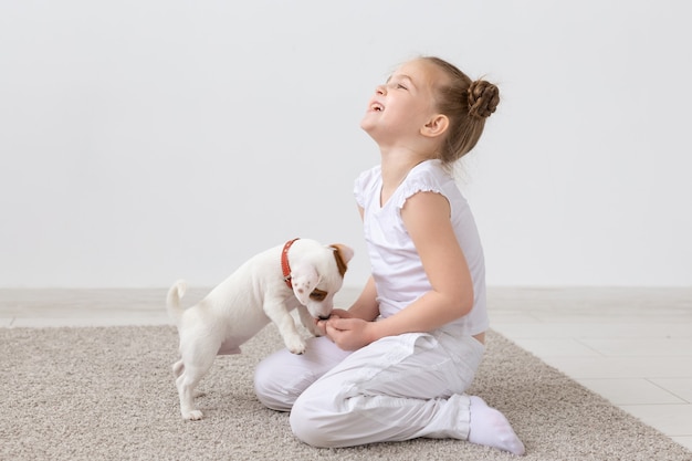 動物 子供 ペットのコンセプト かわいい子犬と一緒に床に座って遊んでいる小さな子供の女の子 プレミアム写真