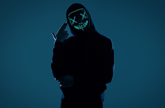 Premium Photo Anonymous Man In Black Hoodie Hiding His Face Behind A Neon Mask